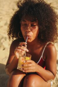 African-American woman with curly hair sipping water through a straw